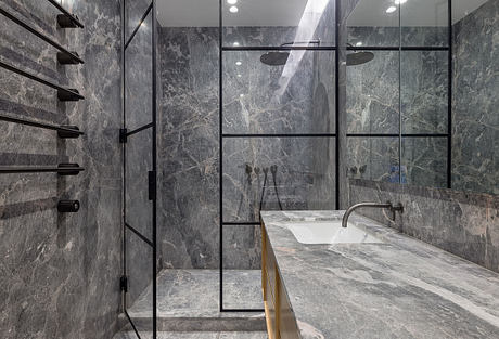 A modern bathroom with gray marble walls, shelves, and a counter with a minimalist sink.
