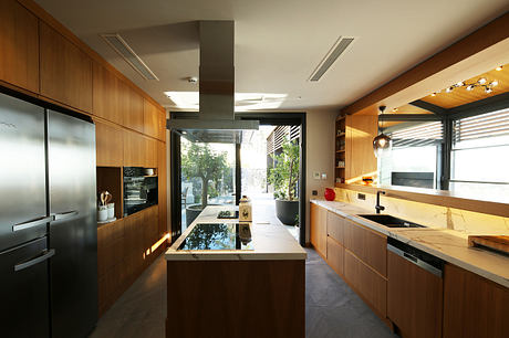 Sleek, modern kitchen with warm wood cabinetry, stone countertops, and floor-to-ceiling windows.