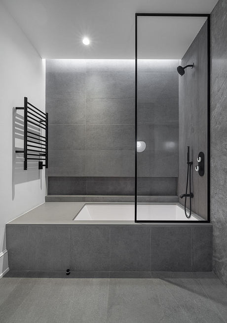 Sleek, modern bathroom with minimalist tile design, frameless glass shower, and built-in tub.