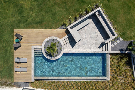Sleek, contemporary pool area with geometric architecture, wood decking, and palm trees.