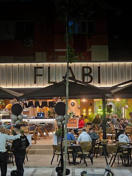Brightly lit cafe with modern furniture, festive decor, and a striking outdoor sign.
