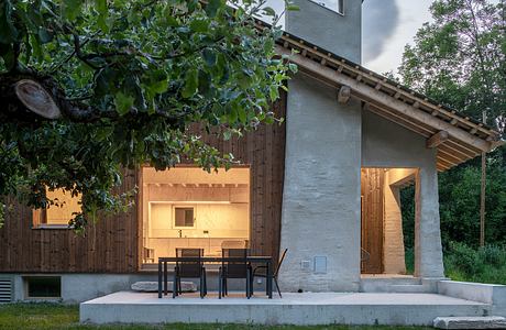 A rustic outdoor patio with wooden accents, a concrete platform, and a towering chimney.