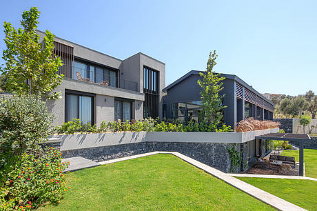 Modern, multi-level home with sleek, geometric design, lush landscaping, and outdoor patio.