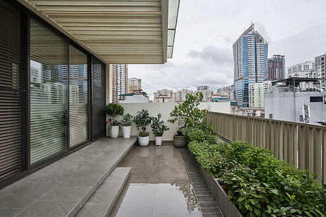 Minimalist balcony with potted plants, glass walls, and a view of the city skyline.
