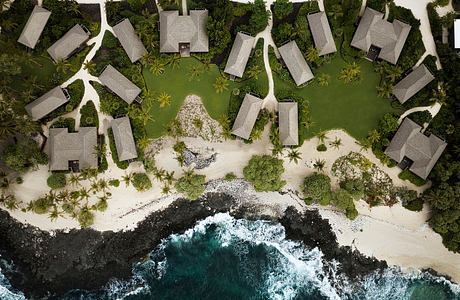 Aerial view of a tropical seaside resort with quaint modular villas nestled among palm trees.