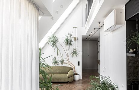 A bright, airy hallway with high ceilings, wood floors, and lush indoor plants.