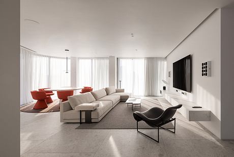 Sleek, modern living room with grey sectional sofa, red accent chairs, and minimalist decor.