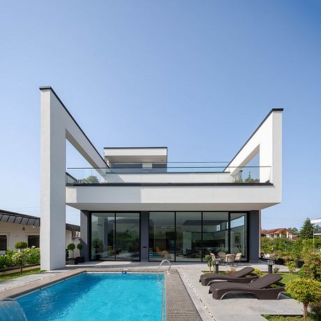 Modern architectural design with sleek, angular lines, glass walls, and swimming pool.