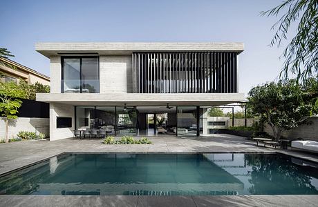 Modern two-story concrete home with sleek lines, large windows, and a swimming pool.