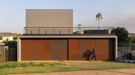 Modern structure with striking orange-tinted facade, large concrete building elements, and lush landscaping.