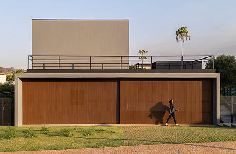 Modern structure with striking orange-tinted facade, large concrete building elements, and lush landscaping.