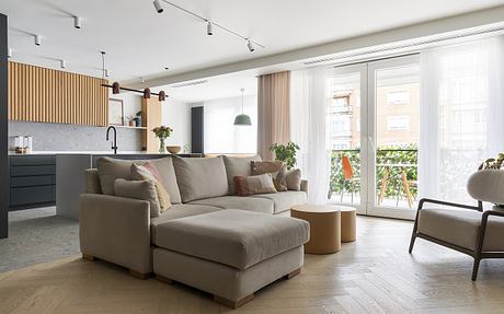 Minimalist modern living room with cozy sectional sofa, wood paneled walls, and large windows.