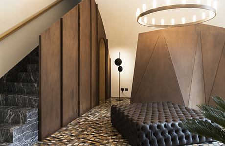 Luxurious interior with dark marble, wooden panels, and a tufted leather sofa under a circular light.