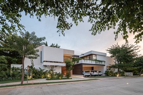 A modern, multi-level home with sleek, geometric forms, balconies, and lush greenery.