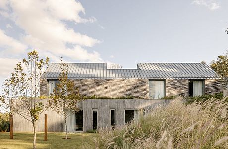 Modern, minimalist home with stone facade, metal roof, and lush landscaping.