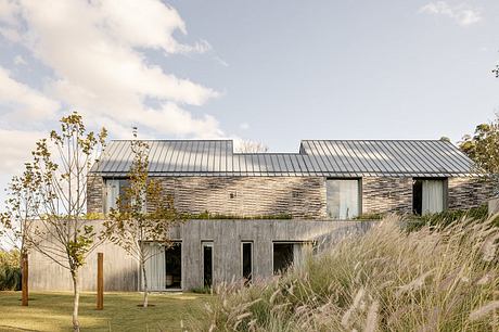 Modern, minimalist home with stone facade, metal roof, and lush landscaping.