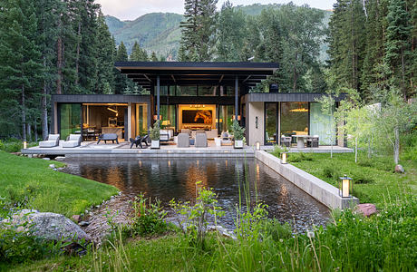 A modern lakeside retreat with an open, glass-walled design and a tranquil pond.