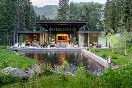 A modern lakeside retreat with an open, glass-walled design and a tranquil pond.