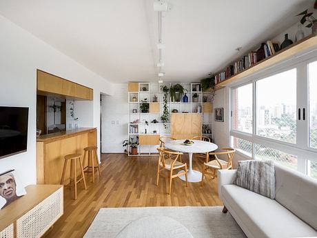 Bright, modern apartment with wood floors, built-in shelving, and cozy seating area.