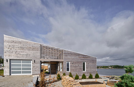 Distinctive architectural features, including a slatted facade, large windows, and a gravel entrance.