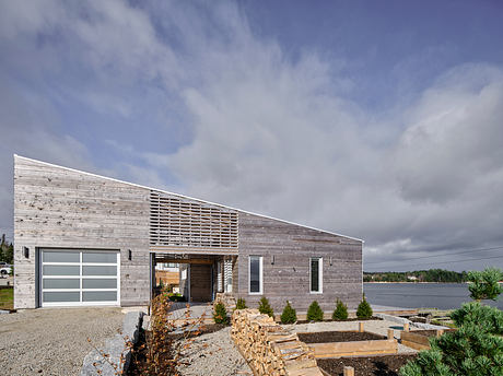 Distinctive architectural features, including a slatted facade, large windows, and a gravel entrance.