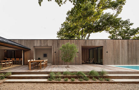 A modern, open-concept home with a wooden exterior, large windows, and a swimming pool.