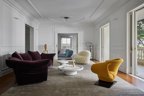 Elegant living room with high ceilings, plush velvet sofa, and modern sculptural chairs.