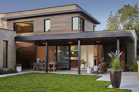 A modern, two-story home with an open-concept design, large windows, and an inviting patio.