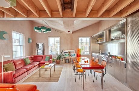 Warm, vibrant open-plan living space with wooden beams, bright furnishings, and modern kitchen.