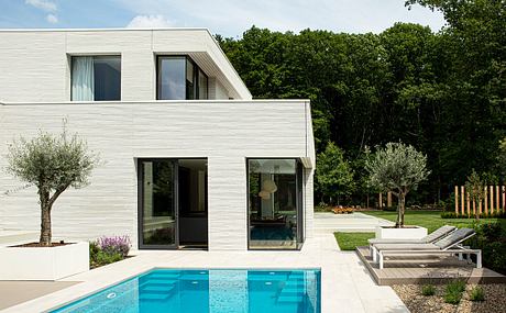 Modern, minimalistic home with sleek, glass-paneled exterior, pool, and landscaping.