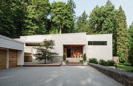 Modern home with clean lines, wood accents, and a welcoming entrance surrounded by lush greenery.