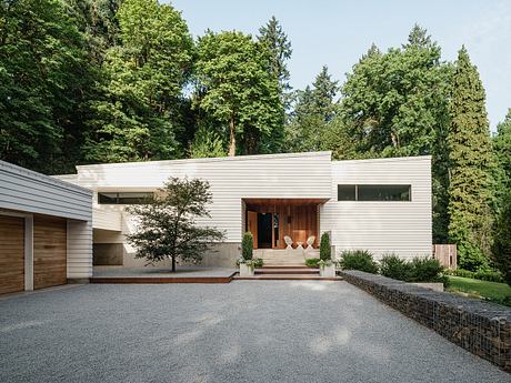 Modern home with clean lines, wood accents, and a welcoming entrance surrounded by lush greenery.