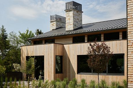 A modern rustic home with stonework chimneys, wooden siding, and large windows.