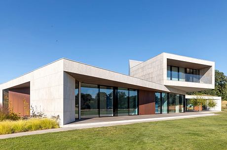 Modern, minimalist structure with glass walls, textured facade, and slanted roofs.