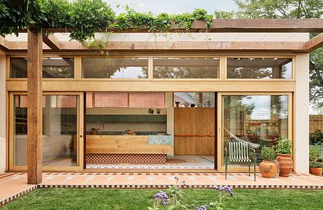 Warm, modern architectural design with wood, glass, and brick elements. Cozy outdoor seating area.