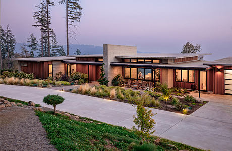 Modern, wood-paneled exterior with expansive windows, landscaped gardens, and a paved walkway.