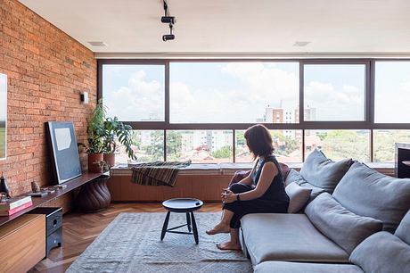 Spacious loft-style room with large windows, exposed brick wall, and modern furnishings.