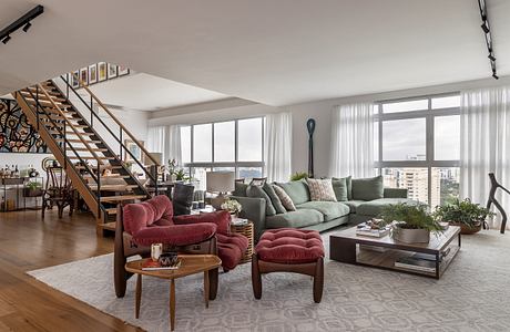 Spacious living room with modern furniture, sleek stairs, and expansive windows.