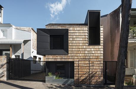 A modern facade with contrasting wooden and dark metal panels, creating an intriguing architectural design.