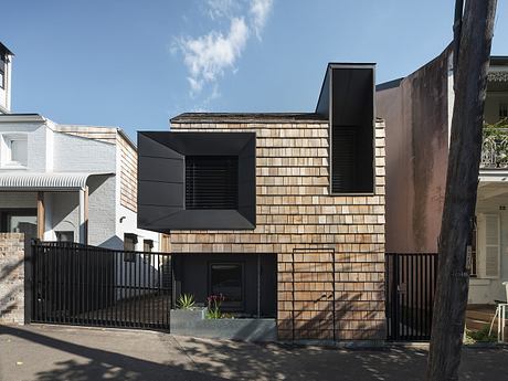 A modern facade with contrasting wooden and dark metal panels, creating an intriguing architectural design.