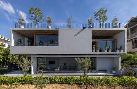 Sleek, modern home with large windows, balcony, and lush landscaping.