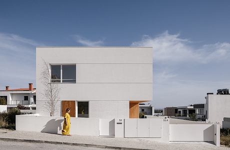 Modern, minimalist residential building with clean lines, large windows, and wooden accents.