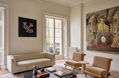 Cozy living room with ornate ceiling, large windows, and eclectic art pieces.