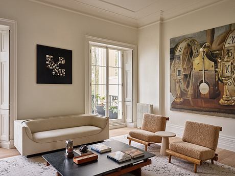 Cozy living room with ornate ceiling, large windows, and eclectic art pieces.