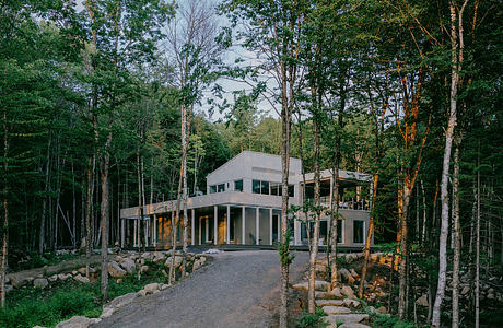 A modern, glass-walled residence nestled in a lush, forested landscape.