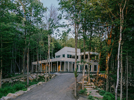 A modern, glass-walled residence nestled in a lush, forested landscape.