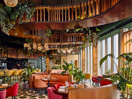 A vibrant, tropical-inspired interior with wooden slat ceilings, lush greenery, and warm lighting.