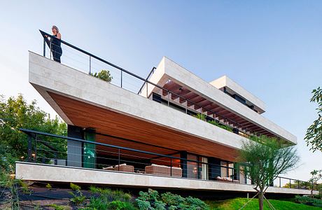 Modern, cantilevered house with a mix of concrete, wood, and lush landscaping.