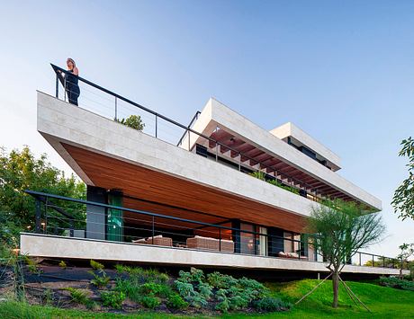 Modern, cantilevered house with a mix of concrete, wood, and lush landscaping.