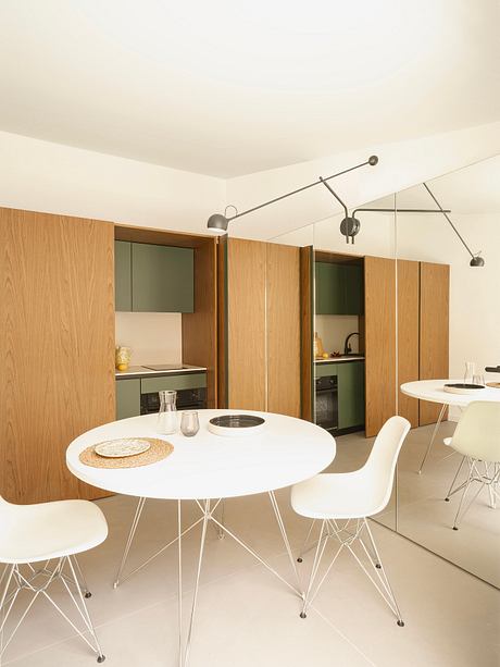 Modern kitchen and dining area with sleek white table and minimalist lighting.